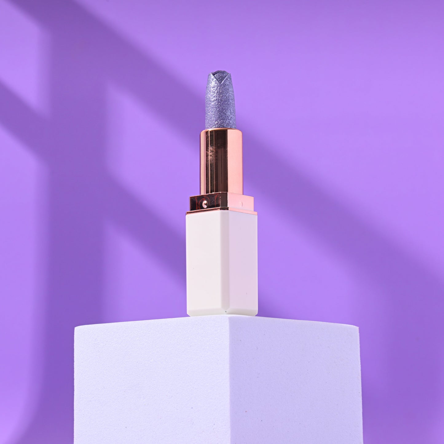 Cocoa Butter Lipstick on pedestal with purple background.