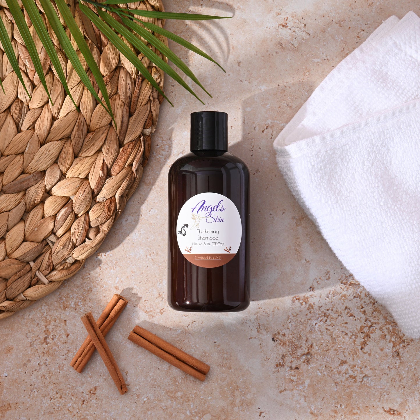 Hair thickening shampoo bottle on a natural textured surface with cinnamon sticks.