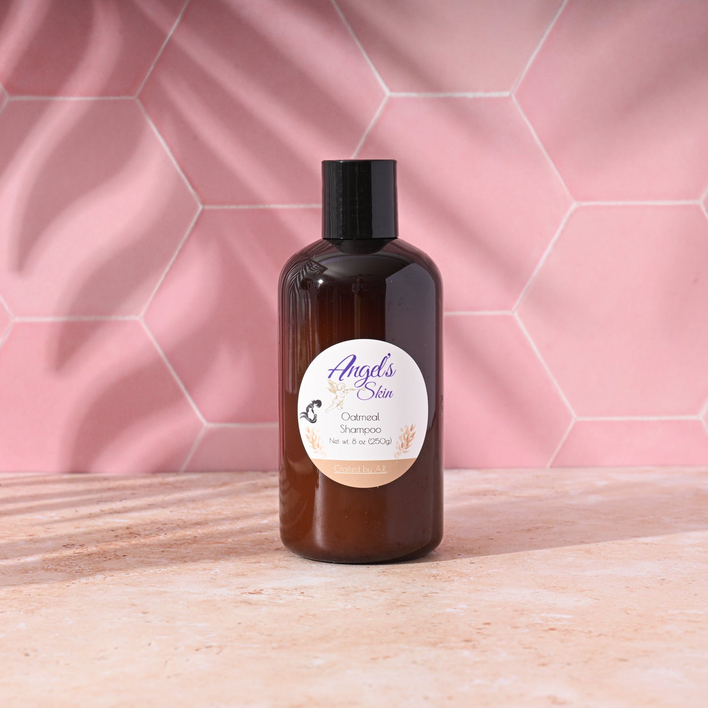 8 oz bottle of Angel's Skin Oatmeal Shampoo on a pink tiled background, soothing and moisturizing for all hair types.