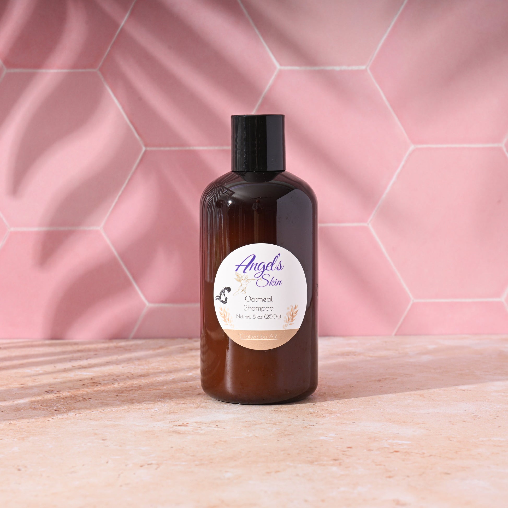 8 oz bottle of Angel's Skin Oatmeal Shampoo on a pink tiled background, soothing and moisturizing for all hair types.