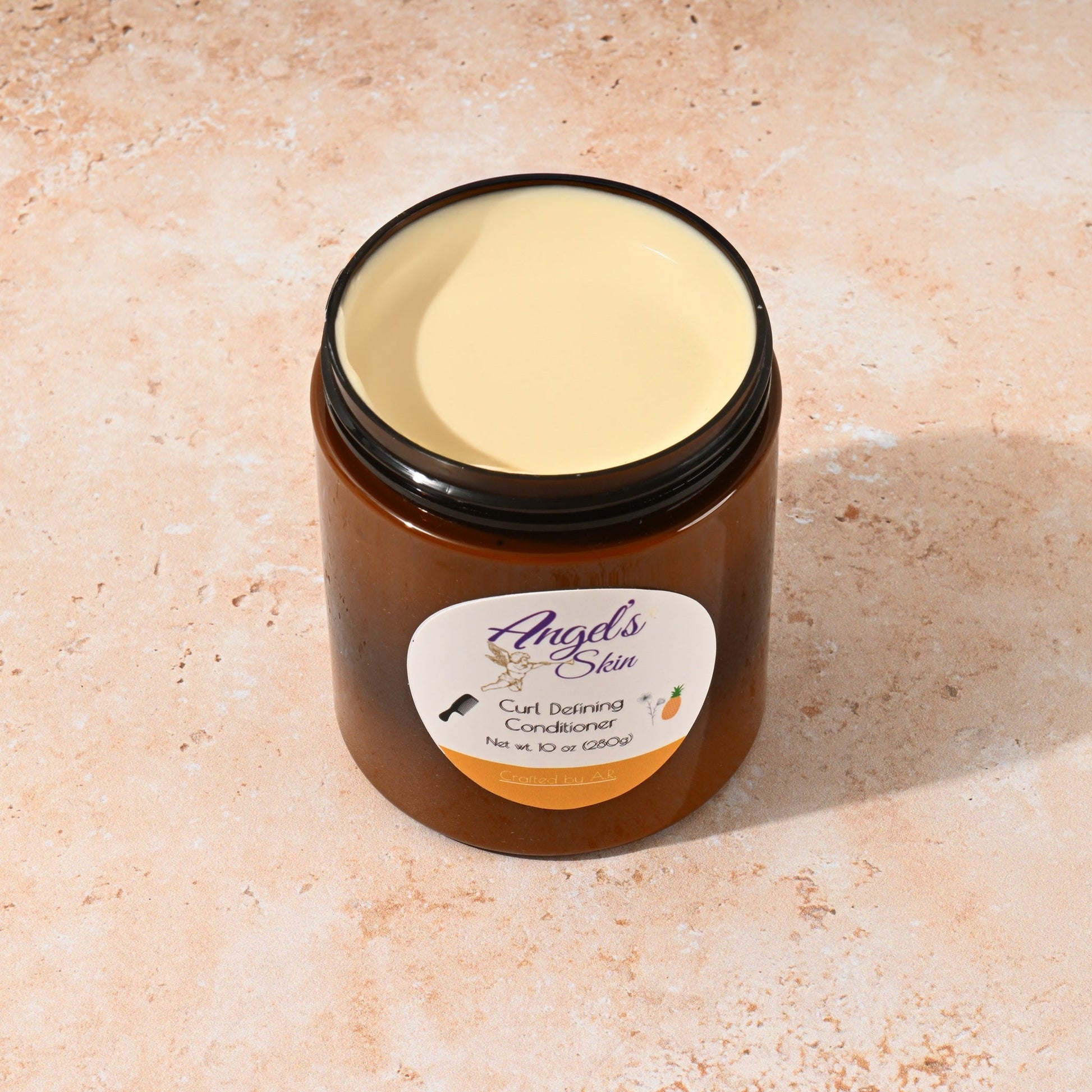 Open jar of Angel's Skin Curly Hair Conditioner cream on a beige surface, designed for maintaining soft, frizz-free curls overnight.